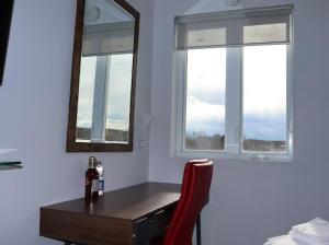um quarto com uma secretária com um espelho e uma cadeira vermelha em AMR Hotel Inc em Saint-Jérôme