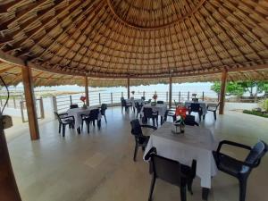 a restaurant with tables and chairs under a straw roof at Cabañas La Española in Coveñas