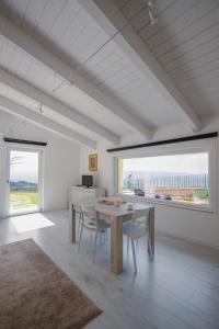 a dining room with a table and chairs and windows at La Meridiana Casa Vacanze in San Vitale