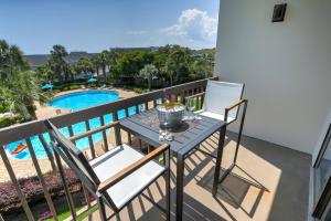 a balcony with a table and chairs and a pool at Pirates Bay A308 in Fort Walton Beach