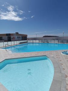 uma grande piscina com água azul num edifício em Apartamento LIFE Complex Amaya Fuerteventura em Costa de Antigua