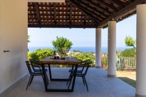 - une table et des chaises sur une terrasse avec vue sur l'océan dans l'établissement Villa Serenità - with private pool and ocean view, à Ricadi