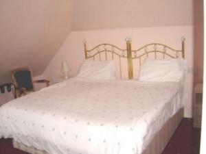 a bedroom with a white bed with a wooden headboard at Alpha Milton Guest House in Cambridge