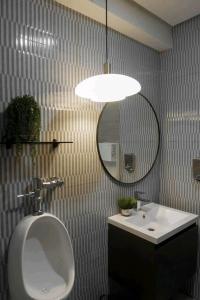 baño con urinario, lavabo y espejo en Twin Hearts Residences Unit 215 en Roxas City