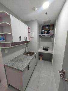 a small kitchen with white cabinets and a sink at Twin Hearts Residences Unit 215 in Roxas City