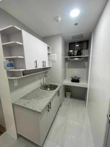 una pequeña cocina con armarios blancos y fregadero en Twin Hearts Residences Unit 215 en Roxas City