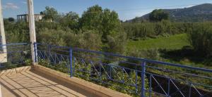a blue railing on a balcony with a view of a field at Mihalis Vrion Apartment in Vrion