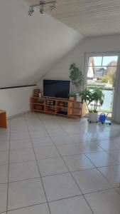 uma sala de estar com televisão e piso em azulejo em Ferienwohnung Begau em Alsdorf