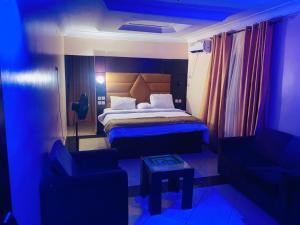 a bedroom with a bed and two chairs and a table at Havilah Suites Ltd, Nnewi in Nnewi