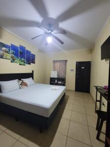 1 dormitorio con 1 cama y ventilador de techo en B Aparts Hotel, en Roatán