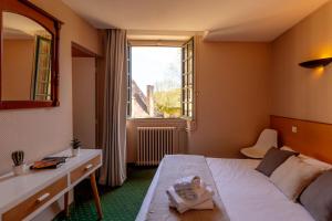 a bedroom with a bed and a desk and a window at Hôtel des Récollets in Sarlat-la-Canéda