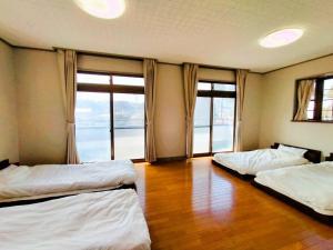 Zwei Betten in einem Zimmer mit Fenstern und Holzboden in der Unterkunft Nikko Big House - Max 12 Guests Near Station 2 Parking in Nikko