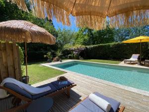 een zwembad met 2 stoelen en een parasol bij Gîte de Fenouil Le Cocon in Civrac-de-Blaye