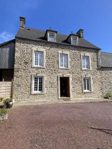 una antigua casa de piedra con un gran edificio en Les Jardins des 3 sœurs, en Quettehou