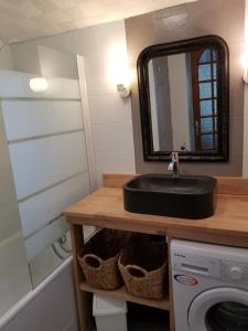 a bathroom with a sink and a washing machine at Les Jardins des 3 sœurs in Quettehou