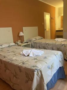 a room with two beds and a table with a phone at HOTEL LOS TILOS RECONQUISTA in Reconquista
