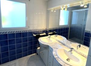 ein blau gefliestes Bad mit 2 Waschbecken und einem Spiegel in der Unterkunft Vacances de charme entre mer et campagne - Ty Meur in Pleumeur-Bodou + 21 Fotos