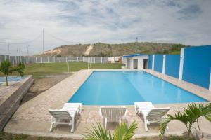 una piscina con sillas y una casa en VILLA VIVA EVENTOS, en Puerto Cayo