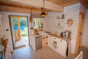 a kitchen with white appliances and a wooden floor at Niezapominajka in Zbiczno