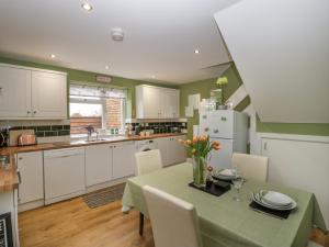 a kitchen with a table with chairs and a kitchen with white cabinets at The Forest Coach House in Cinderford