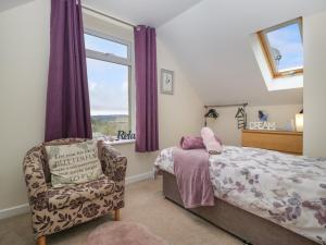 a bedroom with a bed and a chair and a window at The Forest Coach House in Cinderford
