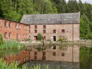 a large brick building next to a body of water at The Forest Coach House in Cinderford