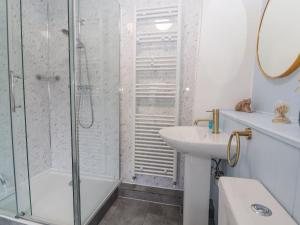 a white bathroom with a shower and a sink at Foxy Lady Cottage in Workington