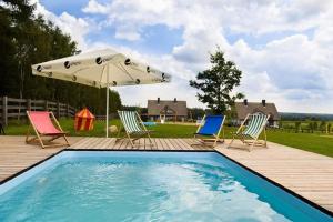 a swimming pool with chairs and an umbrella at Glamping Szelągówka in Sorkwity