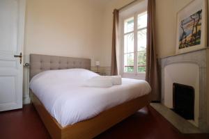 a bedroom with a bed with white sheets and a fireplace at Appartement 1er étage Cottage Reine in Cannes