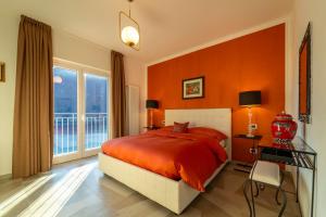 1 dormitorio con paredes de color naranja, 1 cama y ventana en Ka' Doro Deluxe, en Nesso
