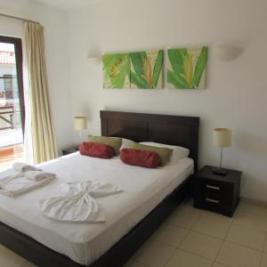 a bedroom with a bed with white sheets and red pillows at Tortuga Beach Resort 3 Bed Villa with pool in Santa Maria