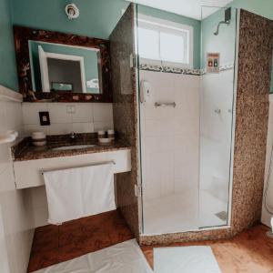 a bathroom with a shower and a sink and a mirror at Pousada Pontal da Praia in São Pedro da Aldeia