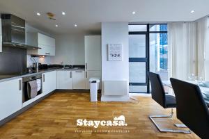 a kitchen with white cabinets and a table and chairs at Serene One-bedroom With Amazing City Views! in Manchester