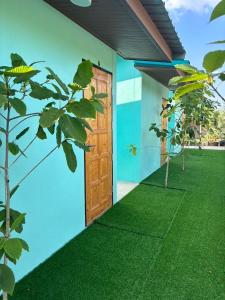 a front door of a house with green grass at BAN SUAN KRATOM CAFE AND RESORT in Nakhon Pathom