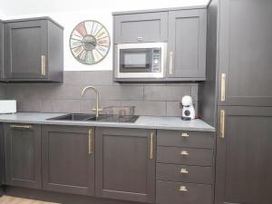 a kitchen with gray cabinets and a sink and a microwave at 4 Lock View in Skipton