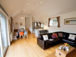 uma sala de estar com um sofá de couro preto e uma cozinha em 4 Fir Garth em Ambleside