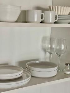 a white shelf with plates and wine glasses on it at Seaport Apartments STUDIO Austral 402 in Ushuaia +51 photos
