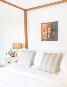 ein Schlafzimmer mit einem weißen Bett mit einem Porträt eines Mannes in der Unterkunft DIX Restaurant & Chambres d'hotes in Saint-Alvère