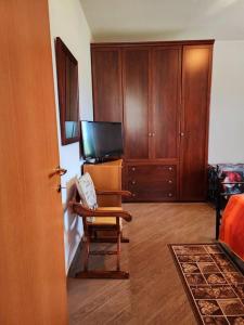 a room with a chair and a tv and wooden cabinets at la casa di simone in Torre Tre Ponti