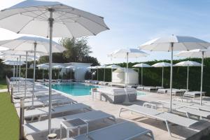 a pool with white lounge chairs and umbrellas at Il Leone Di Mare in Procida