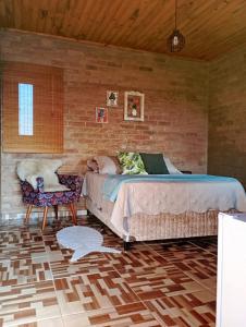 um quarto com uma cama e uma parede de tijolos em Chalés Bons Ventos - Chalé Estrela em São Bento do Sapucaí