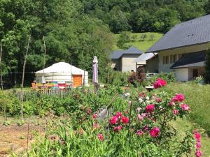 a garden with flowers and a house in the background at Yourte de la bas in Curienne