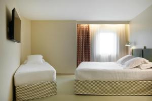 a hotel room with two beds and a window at Hotel des Victoires in Cannes