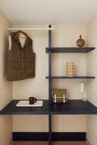 a desk with shelves and a jacket and a purse at Hotel des Victoires - Restaurant in Cannes