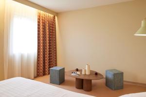 a bedroom with a bed and a table and a window at Hotel des Victoires - Restaurant in Cannes