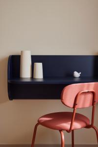 a red chair sitting in front of a black shelf at Hotel des Victoires - Restaurant in Cannes