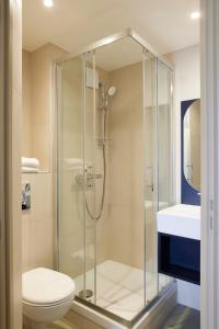 a bathroom with a shower with a toilet and a sink at Hotel des Victoires in Cannes