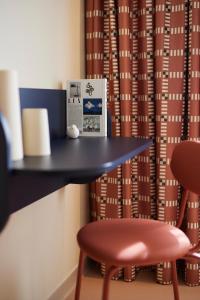 a desk with a stool and a table and a chair at Hotel des Victoires in Cannes