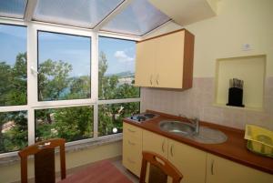 a kitchen with a sink and a large window at Hotel Villa Lastura in Klenovica