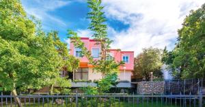 un edificio rosa con árboles delante de él en Hotel Villa Lastura en Klenovica
